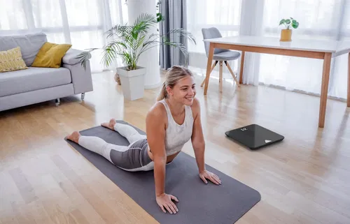 Image of a woman on a yoga mat with Scale beside here.Premium health and fitness products